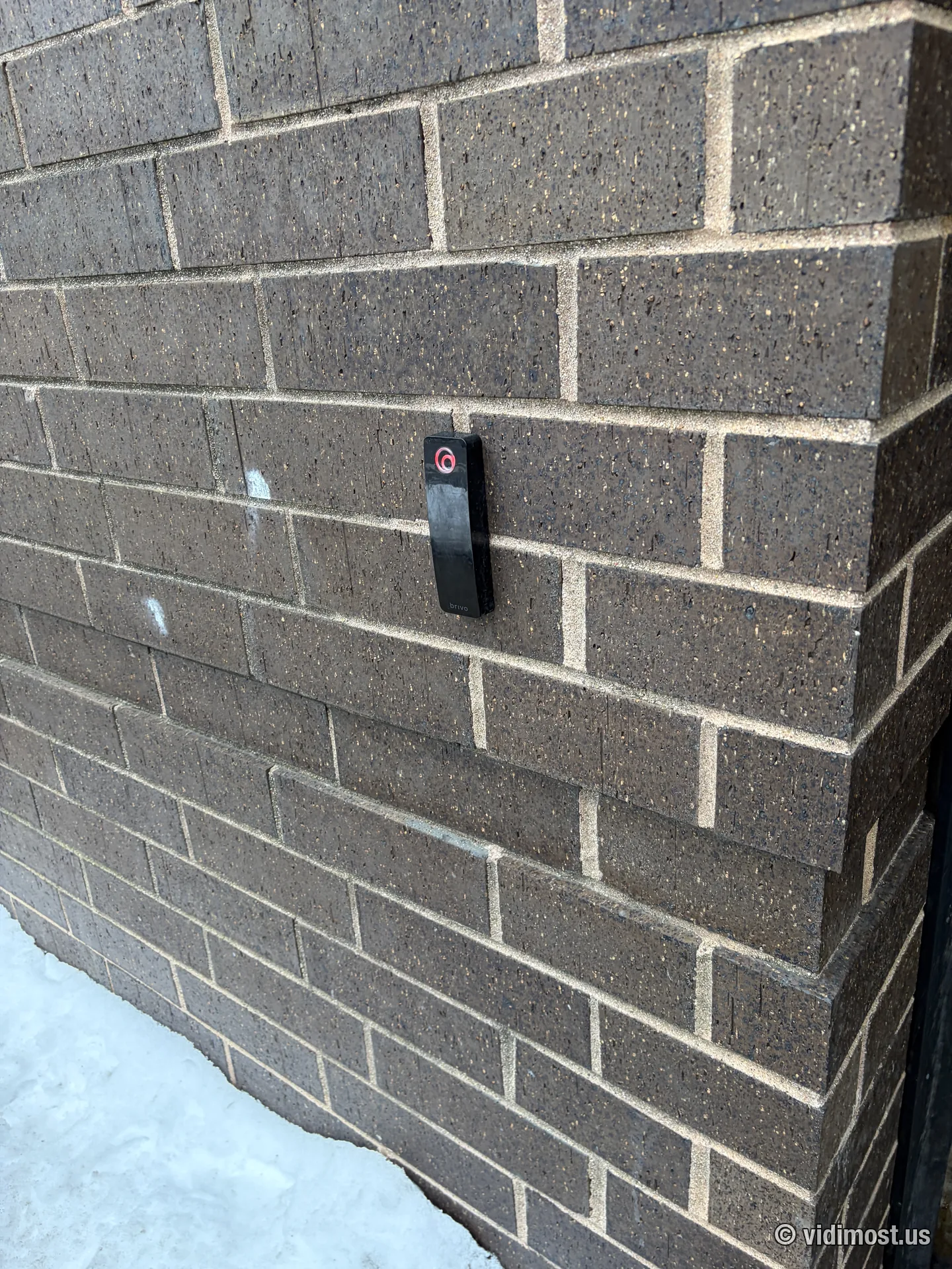 Black Brivo mullion reader on a dark brick exterior wall in Chicago with snow on the ground