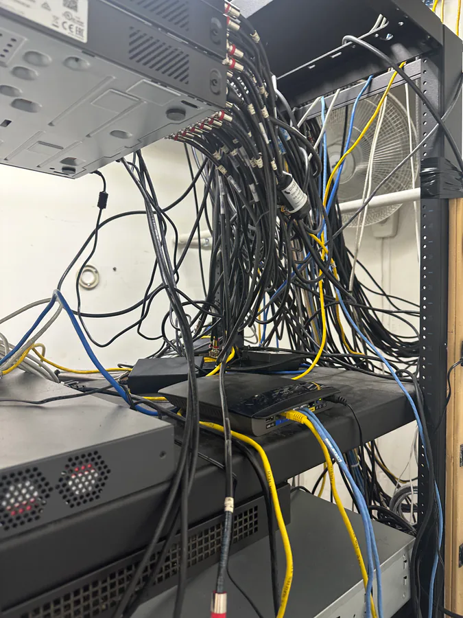 Cluttered, undocumented network rack with disorganized cables — the typical state of an inherited security system before a Vidimost takeover